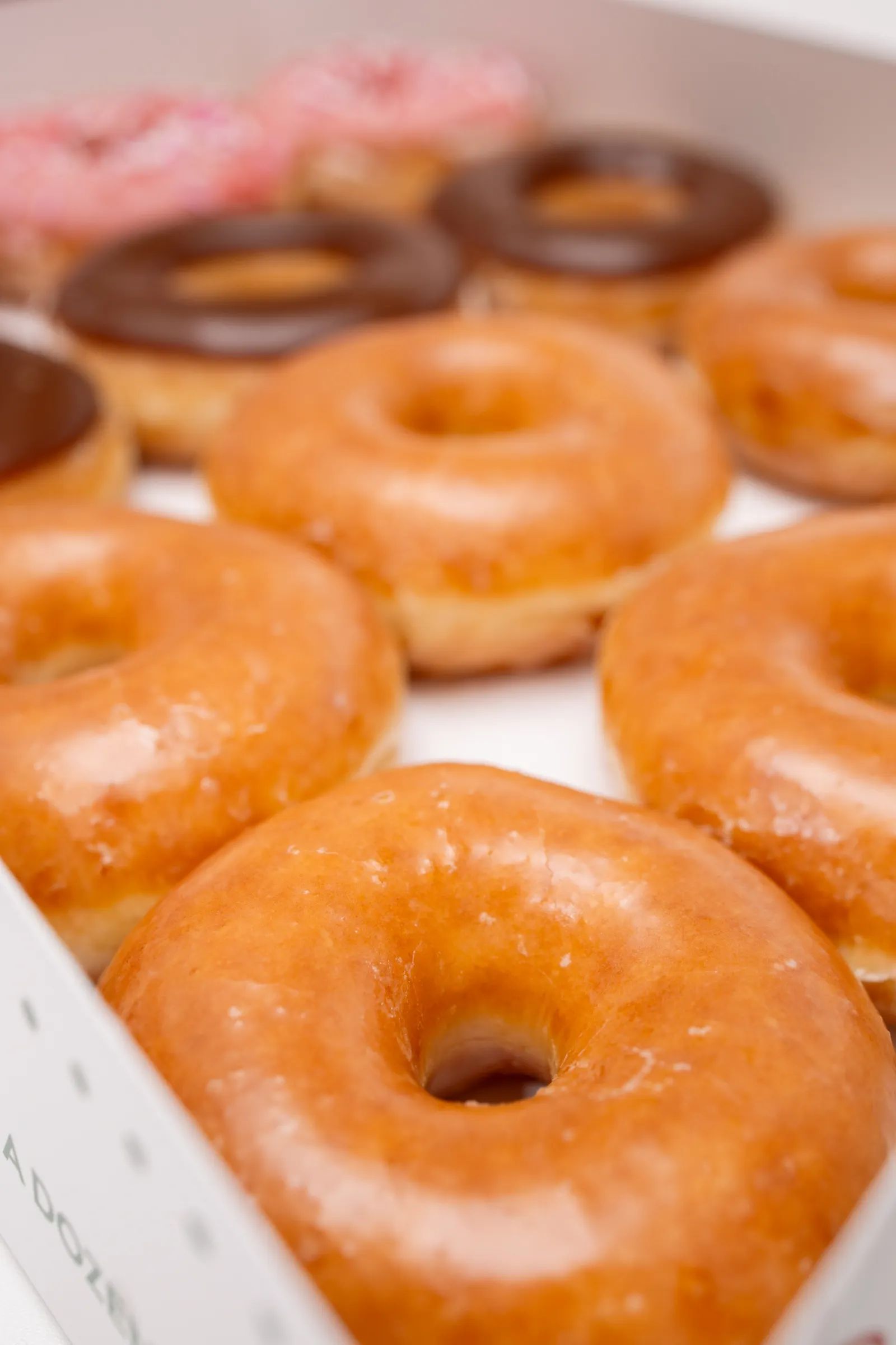 A bakery box of fresh glazed donuts
