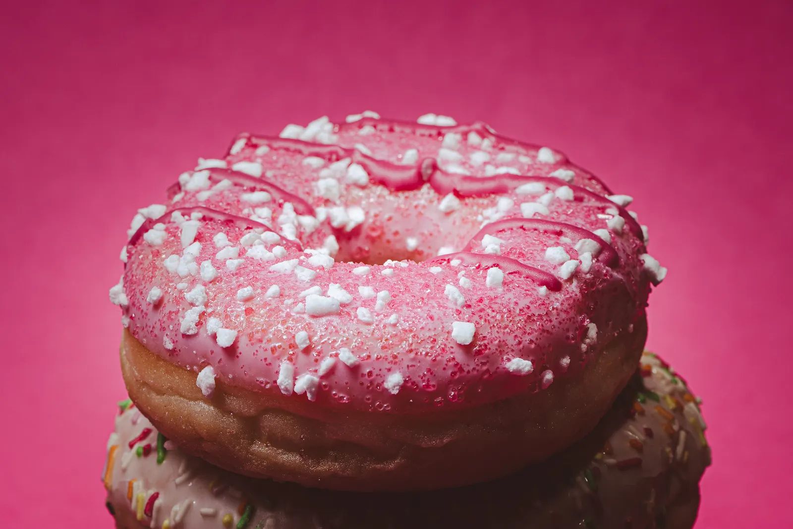 Close-up of a pink frosted donut with sprinkles