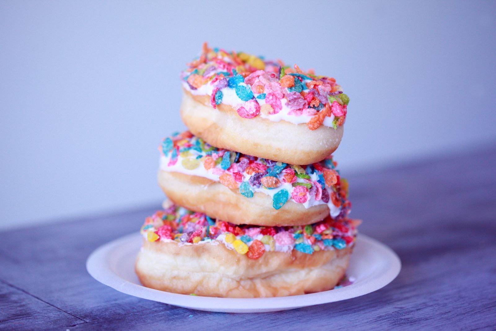 A stack of sprinkle-covered donuts on a plate